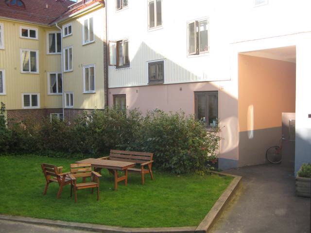 Liten innergård med gräsmatta, trädgårdsmöbler och buskar mellan ljusa flerbostadshus